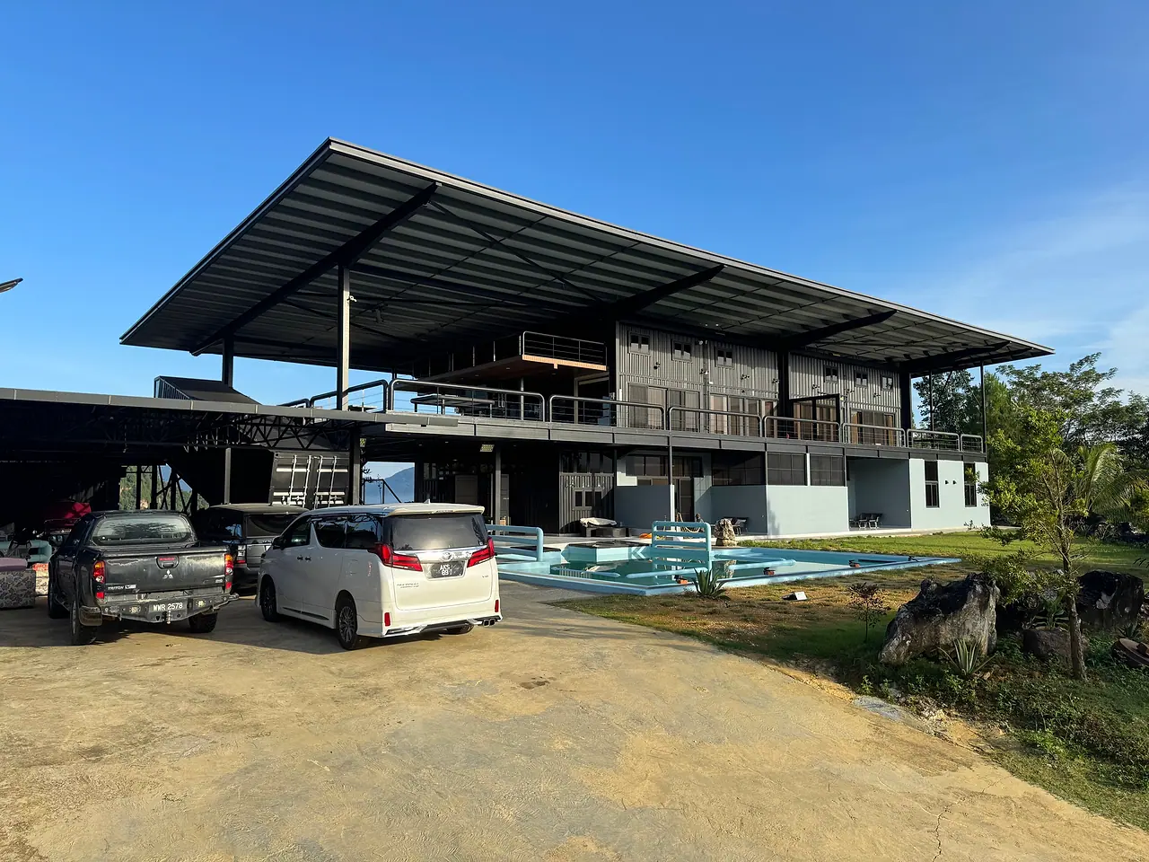 Jef Hill Villa from the driveway: two storeys of steel and timber under one long roof, with the pool in front