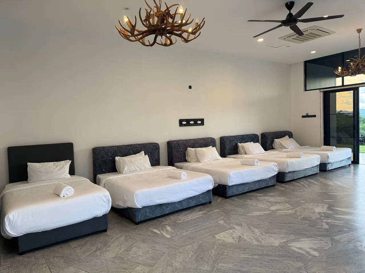Six beds in a row in the family room, with glass doors and the hills beyond