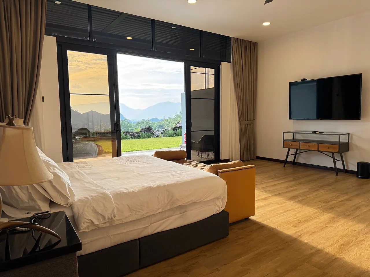 The view from a deluxe king bed: glass doors to the garden, the hills and a wall-mounted TV