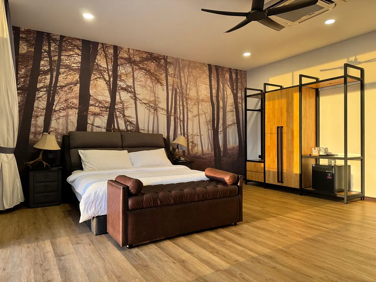 The second deluxe king room: a king bed with a brown leather bench and a forest mural