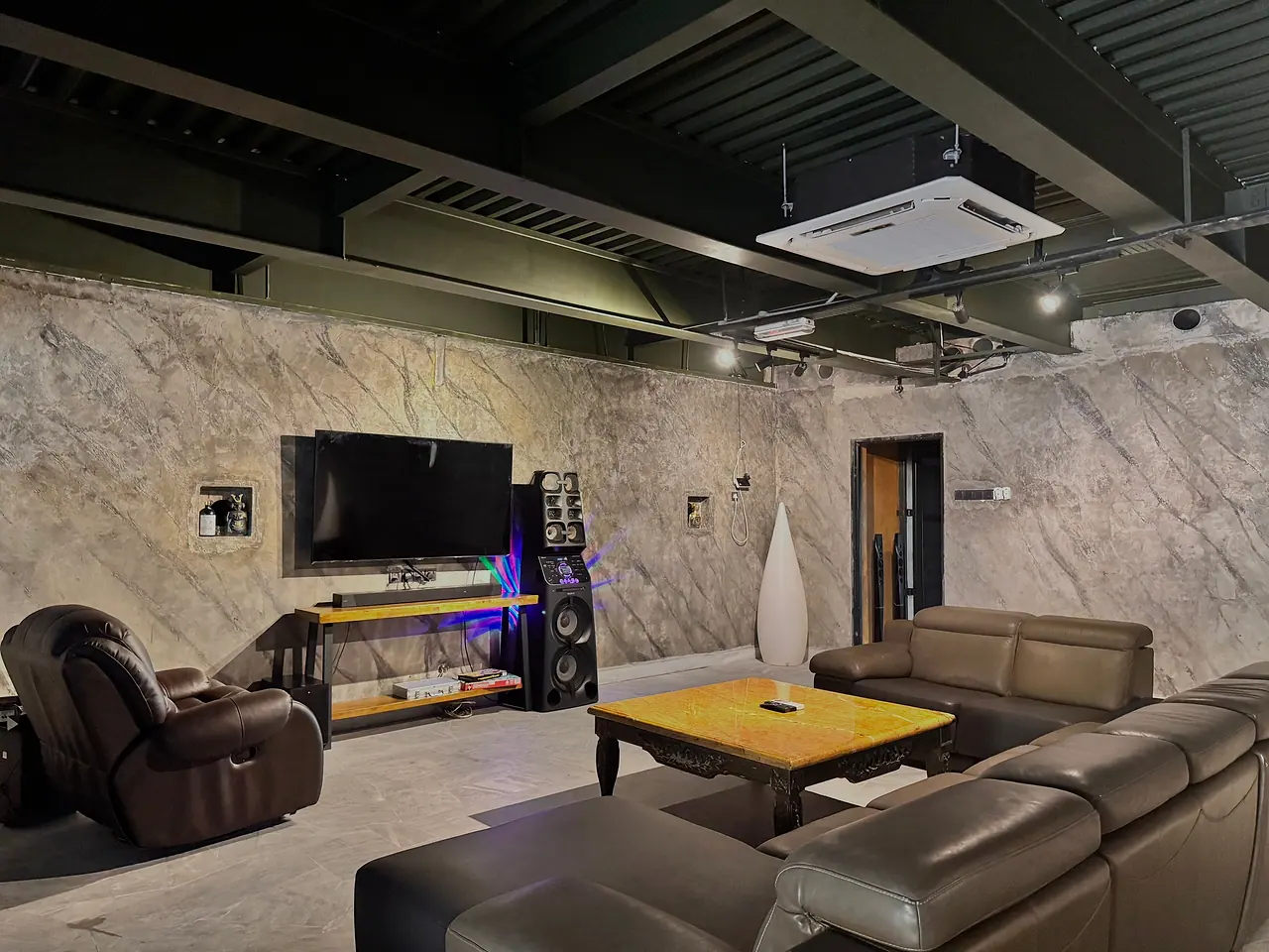 The basement karaoke lounge: leather sofas and recliners, a large TV and tall speakers