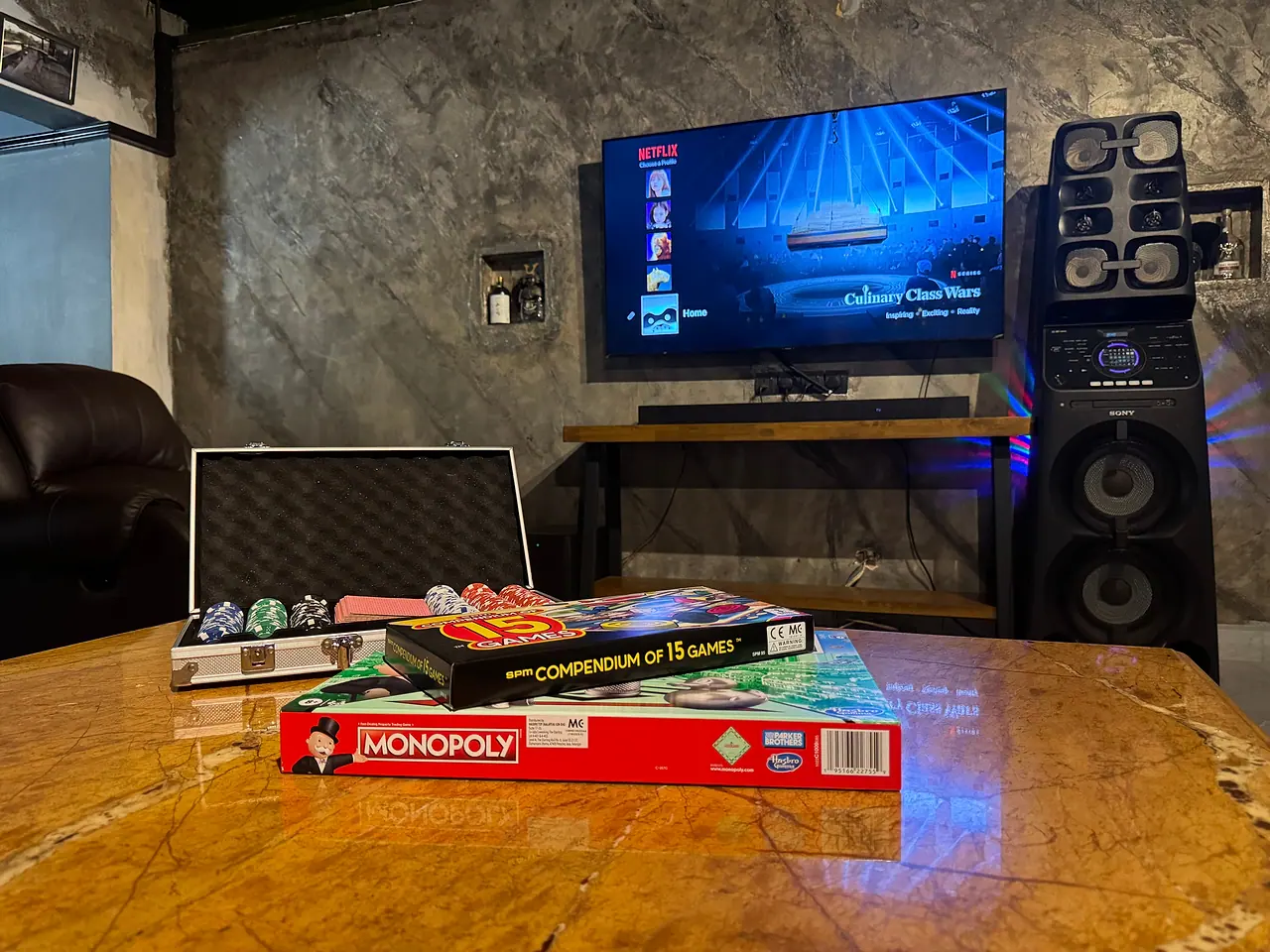 Board games and a poker set on the lounge table, the karaoke screen behind
