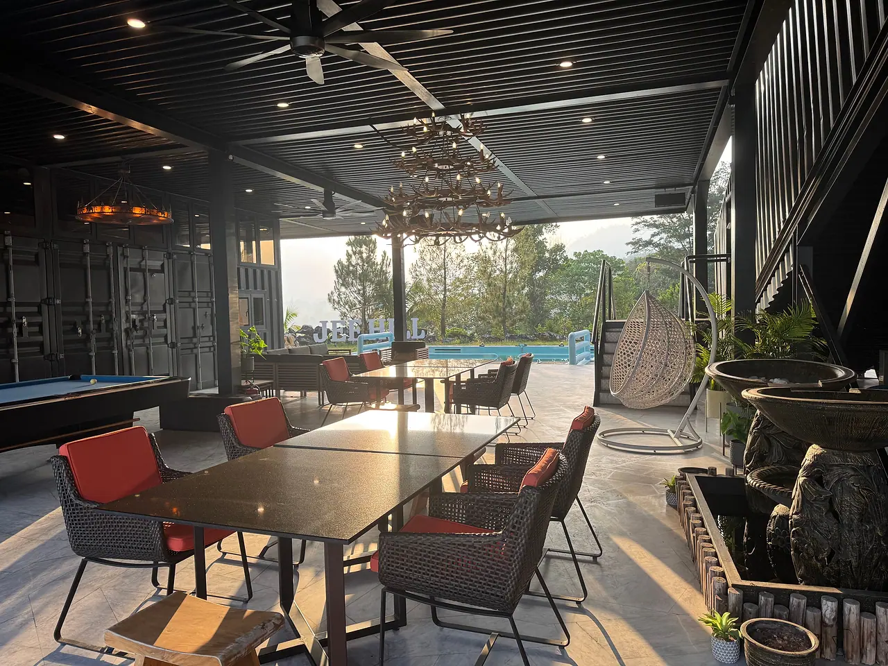 Outdoor dining tables in the pavilion, looking out to the pool and the JEF HILL letters