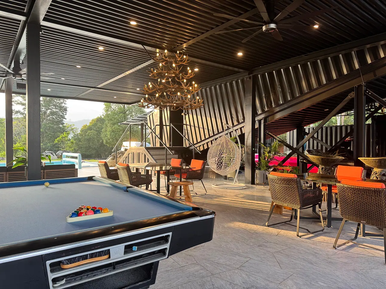 The 9ft pool table in the pavilion, with dining tables, hanging chairs and the pool beyond