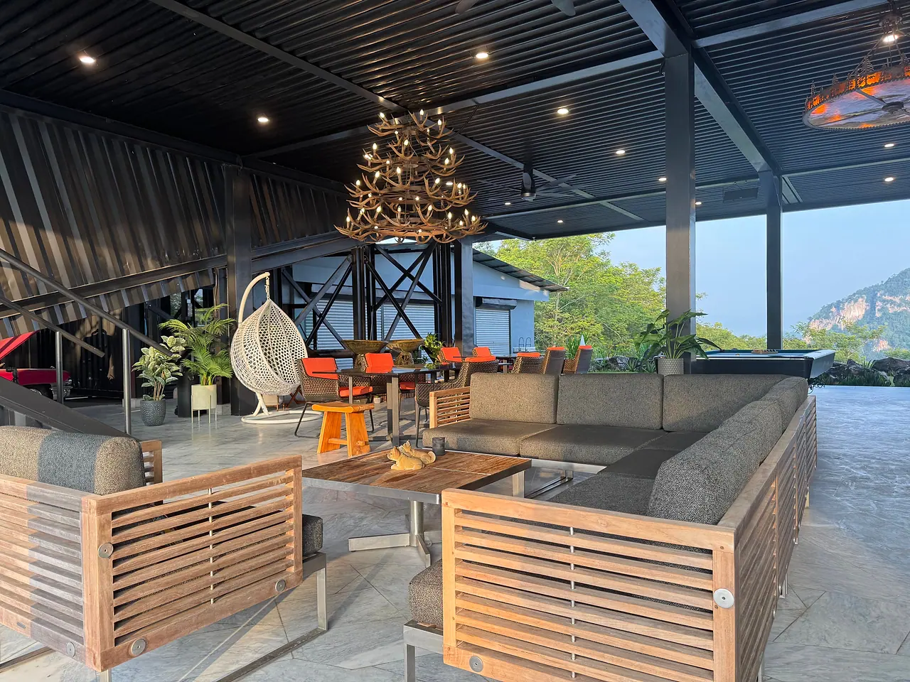 The pavilion lounge in late-afternoon light, its sofas facing the forest and the limestone hill