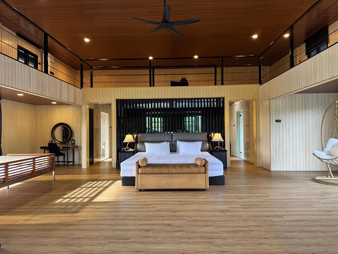 A penthouse suite: the super king bed beneath a high timber ceiling, with a dressing table and a hanging chair