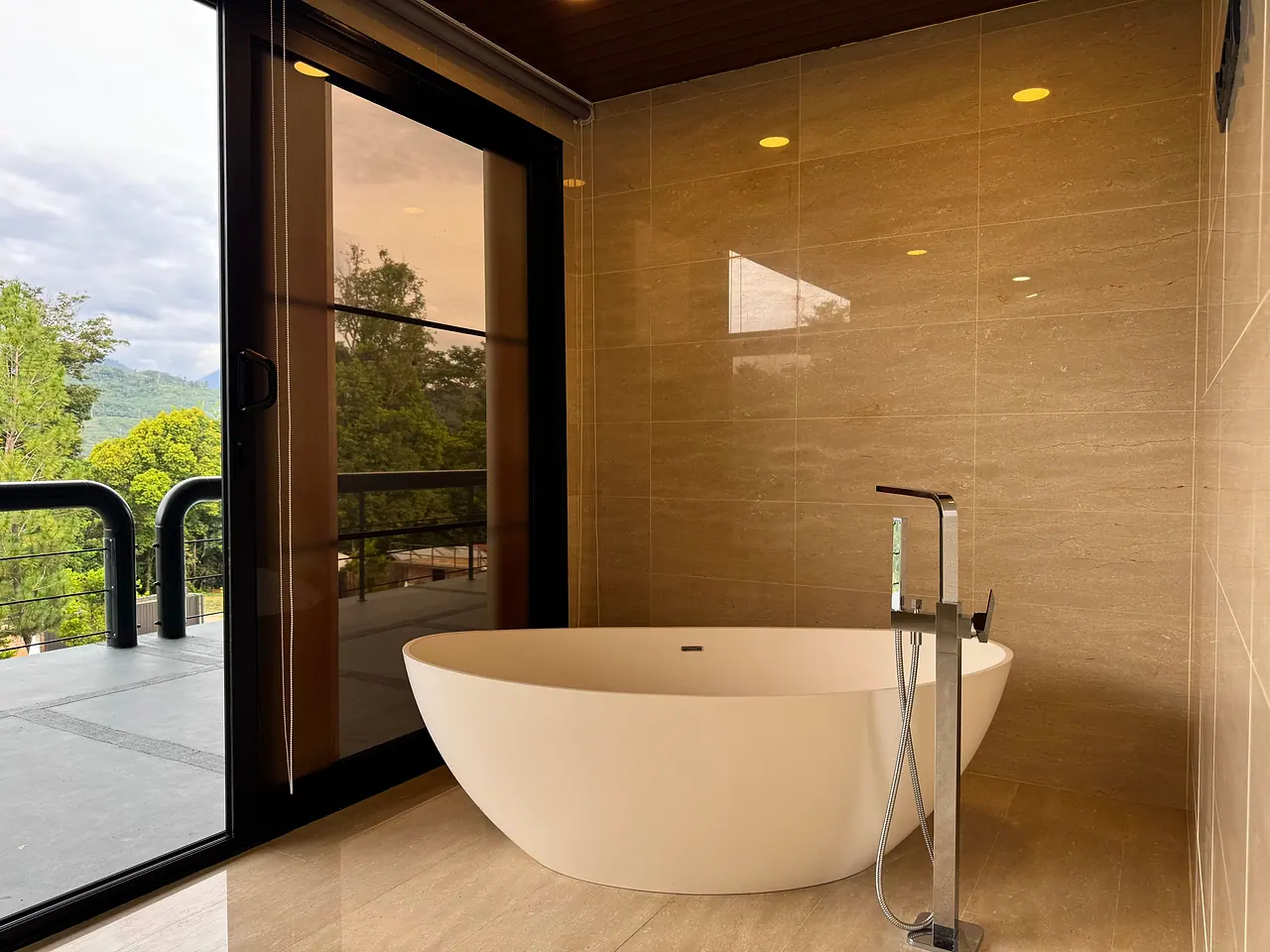 A freestanding bathtub in a penthouse bathroom, beside glass doors to the balcony