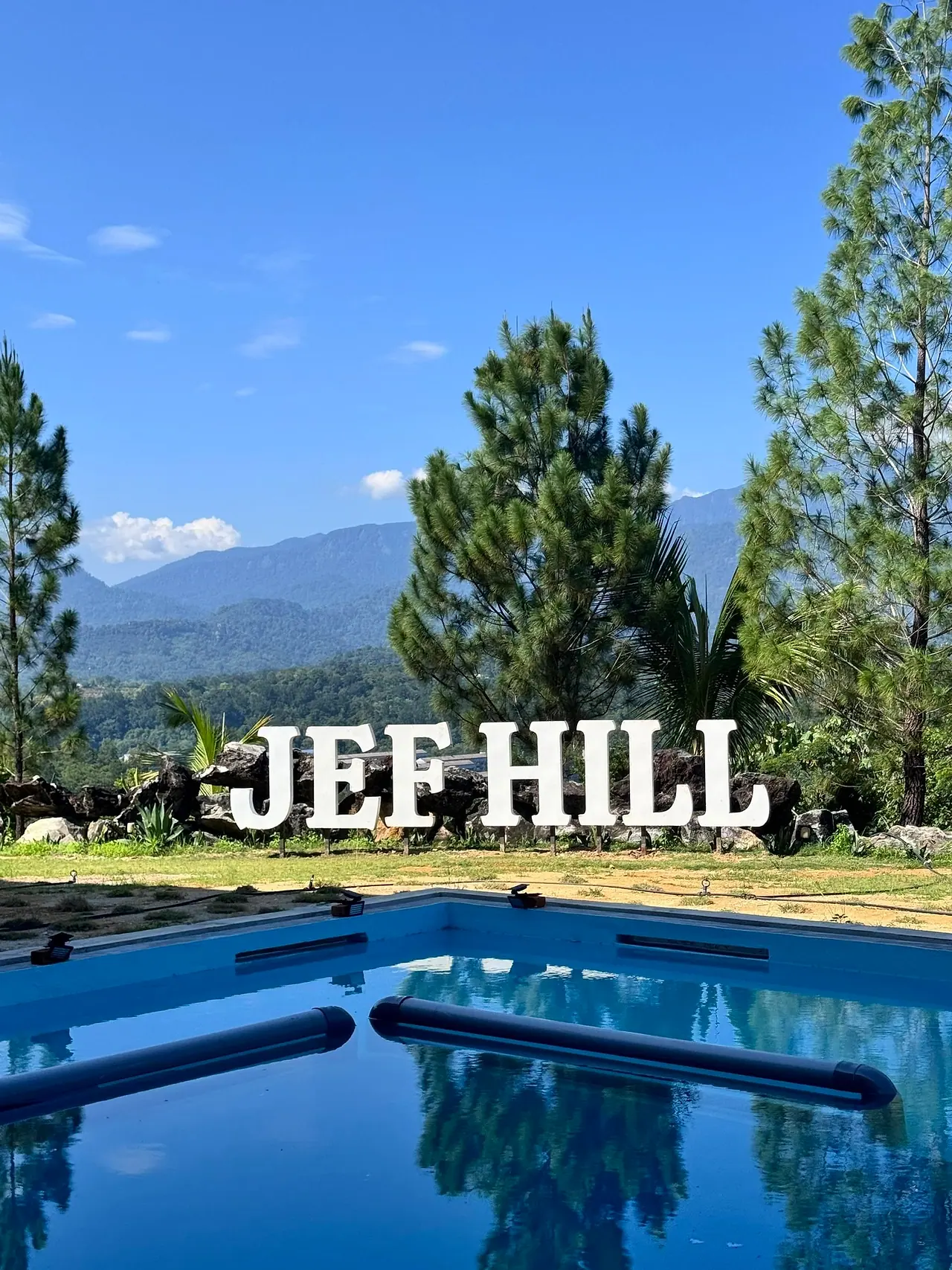 The pool, with the JEF HILL letters, pine trees and mountains behind it