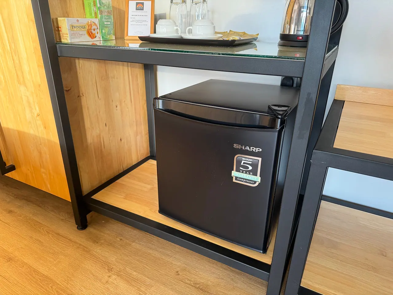 An in-room mini fridge beneath the tea and coffee shelf