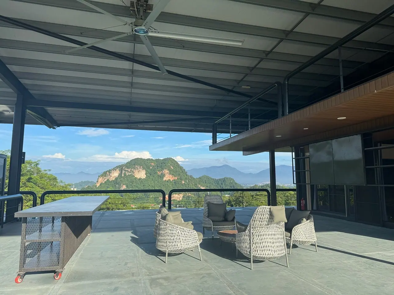 The upper terrace: woven armchairs and a bar counter facing a limestone hill and the valley